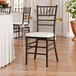 A black wood Chiavari chair with an ivory cushion.