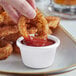 a hand holding a fried onion ring