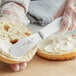 A person using a Choice stainless steel sandwich spreader to spread butter on a piece of bread.