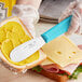 A person using a Choice stainless steel sandwich spreader to spread butter on a piece of bread.