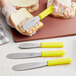 A person spreading food on a sandwich with a Choice knife with a yellow handle.