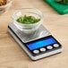 An AvaWeigh digital portion scale with a bowl of greens on top.
