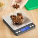 A digital portion control scale with a stainless steel platform and a blue backlit display, shown weighing star anise.