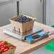A person using an AvaWeigh digital portion scale to weigh strawberries on a counter.
