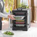 A man using a CaterGator food pan carrier to serve a bowl of salad.