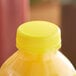 A close-up of a yellow plastic bottle cap on a yellow juice bottle.