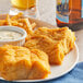 A plate of Zatarain's Seasoned Fish Fri with fries and white sauce next to a glass of beer.