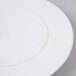 A Wilton white plastic cake separator plate with text on the lid