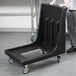 A person pushing a black Cambro Camdolly.