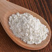 A wooden spoon full of Saf Pro Softness & Volume Dough Improver powder.