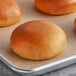 A tray of bread rolls on a brown table with a Saf Pro Dough Improver label.