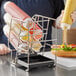 A hand using a FIFO Innovations countertop squeeze bottle holder to pour mustard on a sandwich.