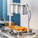 A countertop Avantco heat lamp with trays of fried chicken on a counter.