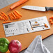 A Mercer Rules Spanish reference tool on a cutting board with vegetables and a knife.