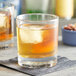 A Pasabahce double old fashioned glass with a drink and ice cubes.