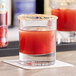 A Pasabahce old fashioned glass filled with a brown cocktail garnished with red and white.