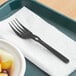 a fork on a napkin and fruit