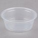 A Dart clear plastic souffle container on a gray surface.