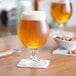 Two Pasabahce stemmed beer glasses on a table.