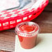 A Solo clear plastic lid on a small cup of red liquid on a table.