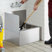 A person cleaning a floor with a mop in a stainless steel mop sink.