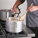 a large silver pot with a wooden spoon on top of a stove