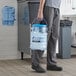 A man in a chef's uniform using a San Jamar Shorty Saf-T-Ice polycarbonate container to carry ice.