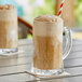 An Acopa glass beer mug filled with brown liquid and a straw.