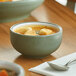 A bowl of soup with croutons on a table with a spoon.