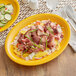 An Acopa Capri mango orange oval stoneware platter with meat and vegetables on it.