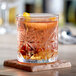 An Acopa Gardenia rocks glass with orange juice and a slice of orange on top.