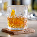 An Acopa Gardenia rocks glass with a drink on a coaster.