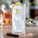 A close-up of an Acopa Gardenia highball glass of water with a lemon slice.