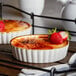 A white tray with two Acopa Keystone stoneware dishes of dessert with strawberries on top.