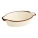An oval porcelain baker or casserole dish with a vanilla bean color and brown rim.