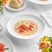 A white Acopa Liana soup bowl with food on it.