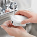 A person washing hands with a white Carlisle Sparta hand and nail brush.