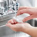 A person washing their hands with a Carlisle Sparta hand and nail brush.