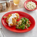 An Acopa Capri Passion Fruit Red stoneware platter with food on a table.