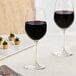 Two Acopa Covella wine glasses on a table with wine.