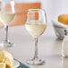 Two Acopa all-purpose wine glasses of white wine on a table.