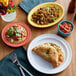 A table with Acopa Capri Caribbean Turquoise Stoneware Bouillon bowls and plates of food.