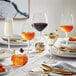 Acopa Radiance tall stemless wine glasses on a table with glasses of drinks.