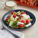 A plate of salad with chicken, raspberries, and pecans on an Acopa Keystone Azora Blue stoneware coupe plate.