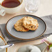 An Acopa Keystone granite gray stoneware coupe plate with cookies and tea on it on a table.