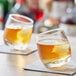 Two Acopa Select Rocking Rocks glasses of brown liquid on a napkin.