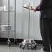 A woman in a black uniform using an American Metalcraft stainless steel plate cover.