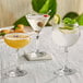 A table with a group of Acopa Empire coupe glasses filled with different colored drinks.