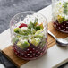 Two Acopa hobnail glass bowls filled with food on a table.