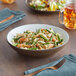 An Acopa Embers hickory brown matte stoneware pasta bowl filled with pasta with shrimp and asparagus on a table.